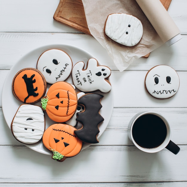 Photo preparation for halloween. coffee and scary gingerbread cookies on a wooden background.