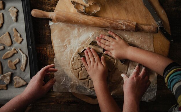 Preparation for the holiday Bakery Female hands and a child make a cut from the rolled cookie dough