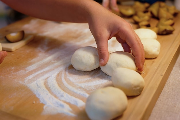 Foto preparazione di gnocchi di frutta fatti in casa con prugne specialità ceca di dolce buon cibo pasta sul tavolo di legno della cucina con le mani