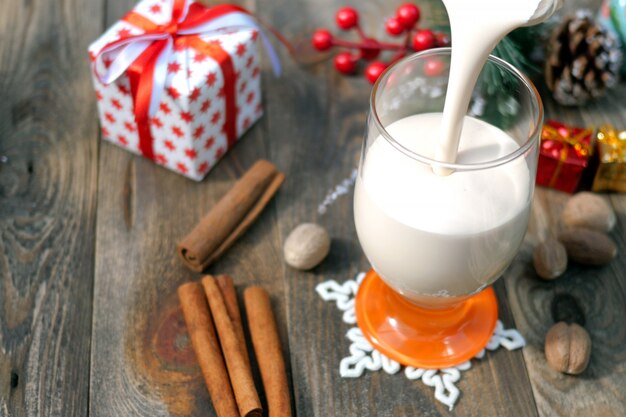 Preparation homemade traditional christmas spicy drink eggnog with ground nutmeg, cinnamon in glass.