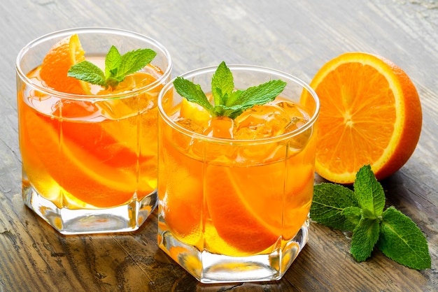 Preparation of the lemonade drink. Lemonade in two glass and lemon with mint on the table outdoor.