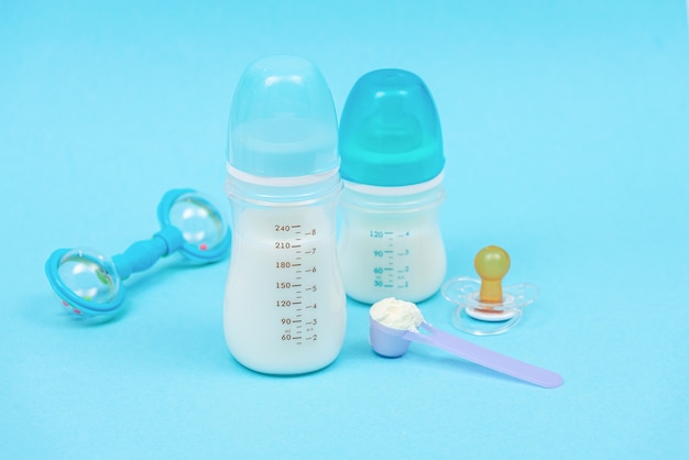 Preparation of mixture baby feeding with infant formula powdered milk in bottle with toys