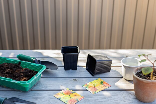 Photo preparation for planting flower seeds garden tools, seedling pots, soil on a wooden table in the backyard