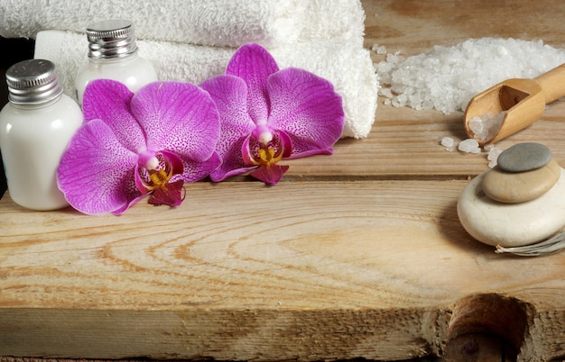 Preparation for spa procedures, salt, towels, lotion and bright orchid flowers