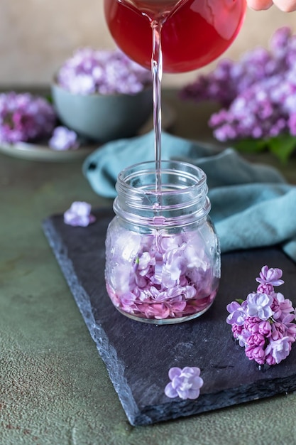 Photo preparation of syrup from the lilac flowers glass jar of homemade lilac syrup