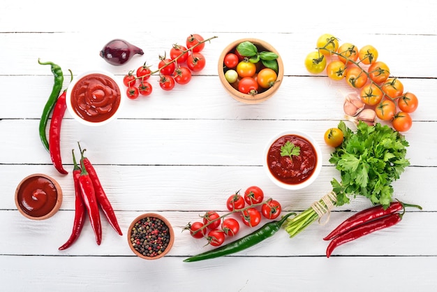 Preparation of tomato sauces and seasonings Cherry tomatoes spices chili peppers Top view On a white wooden background Free copy space