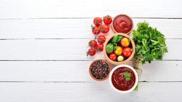 Preparation of tomato sauces and seasonings Cherry tomatoes spices chili peppers Top view On a white wooden background Free copy space