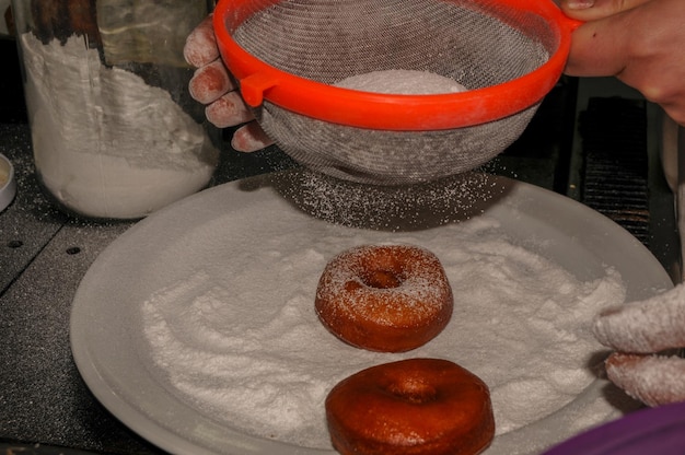 Preparation of traditional donuts sprinkled with icing sugar