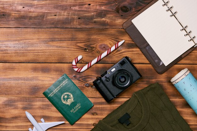 Preparation for travel concept - Toy plane, camera, cup of tea, clothes on wooden background.