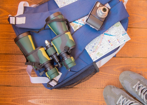 The preparation for the trip travel backpack binoculars camera map on wooden background