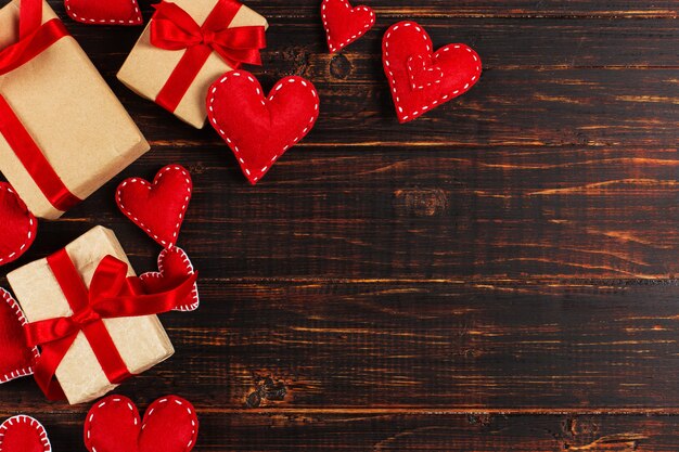 Preparation for Valentine's Day. Red hearts and craft gifts on wood. Copy space