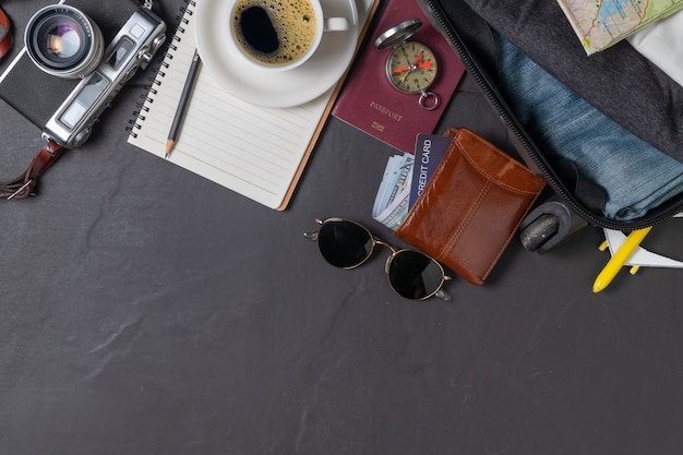 Prepare a suitcase,  vintage camera,  notebook, passport, map and hot coffee on the black tiled floor and copy space. travel concept