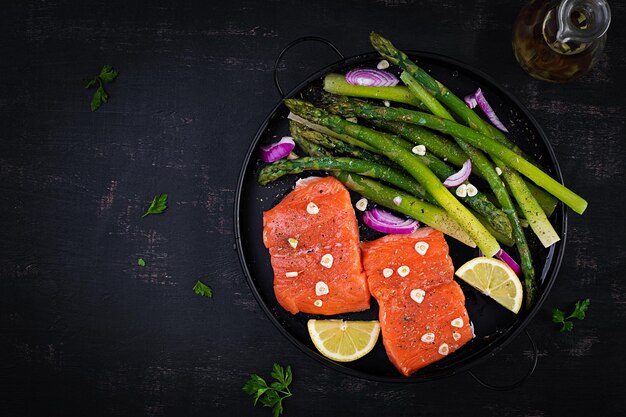 Prepared for baking salmon with asparagus lemon slices and spices on dark table Top view flat lay