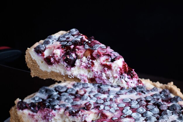 Prepared berry pie on the table in the kitchen the cook cuts a piece of a separate blurred surface