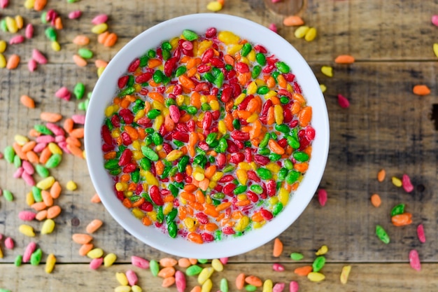 Prepared breakfast with milk and colorful puffed rice in the bowl with spilled rice in the background