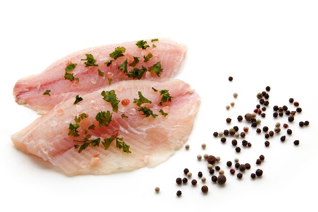 Prepared raw white fish fillet sprinkled with pink salt and herbs