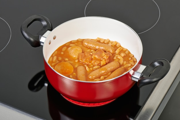 Preparing cassoulet in red ceramic pan