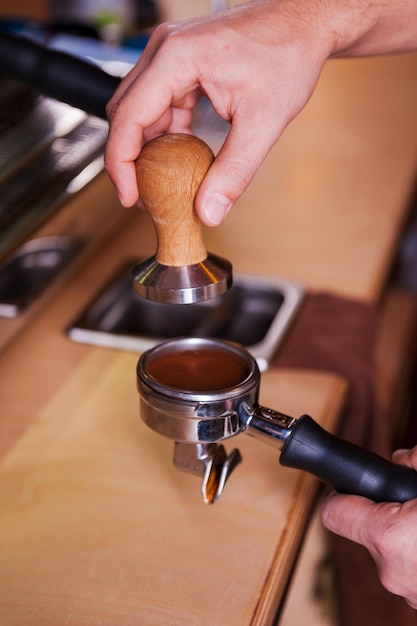 Preparing coffee. Close-up image of male barista preparing fresh coffee at the bar counter