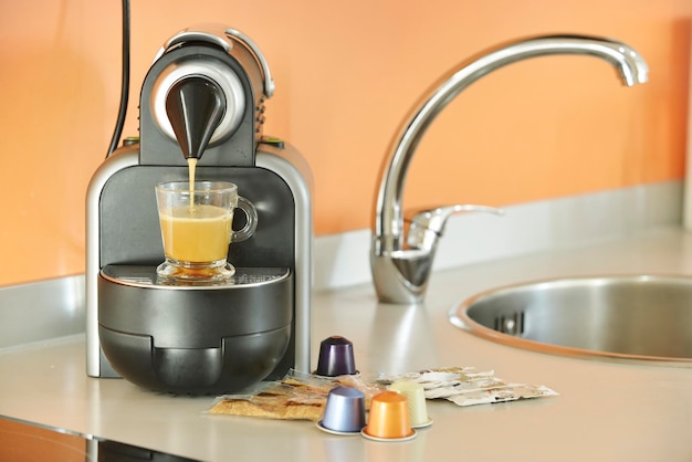 Preparing a coffee with milk in a kitchen with a coffee capsule machine with a gray countertop