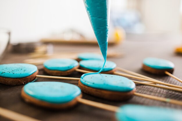 Preparing easter cookies with blue icing for decoration on rustic wooden table closeup