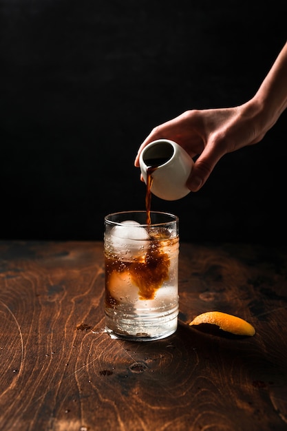 Preparing espresso tonic with orange juice.