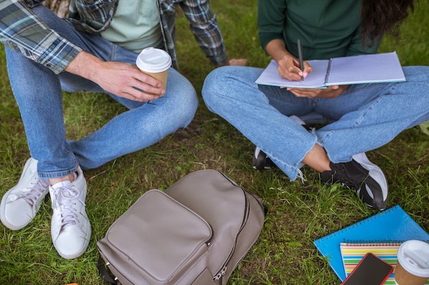 Preparing to exams. A group of young people sitting on the grass and getting ready for the exams