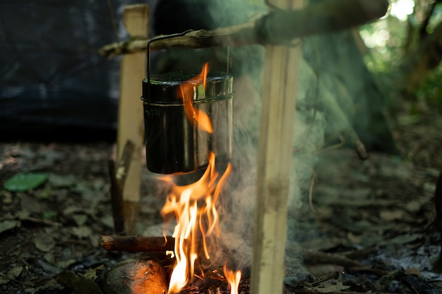 Preparing food on campfire, cooking in forest.