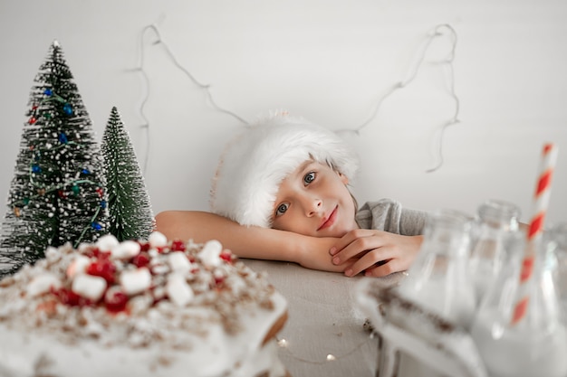 Photo preparing food for christmas dinner a boy in red santa hat wants to steal a piece of christmas cake