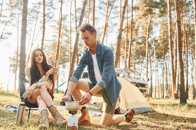 Preparing food Young couple is traveling in the forest at daytime together