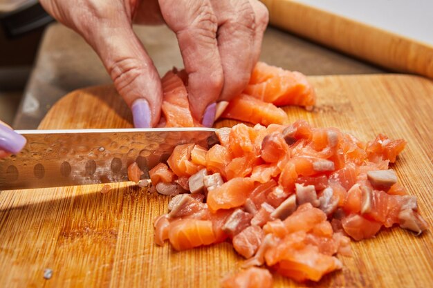 Preparing Fresh Salmon Fillet with Knife on Cutting Board in Modern Kitchen