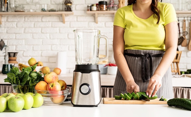 Photo preparing healthy foods healthy eating and dieting young brunette woman making green smoothie at home kitchen