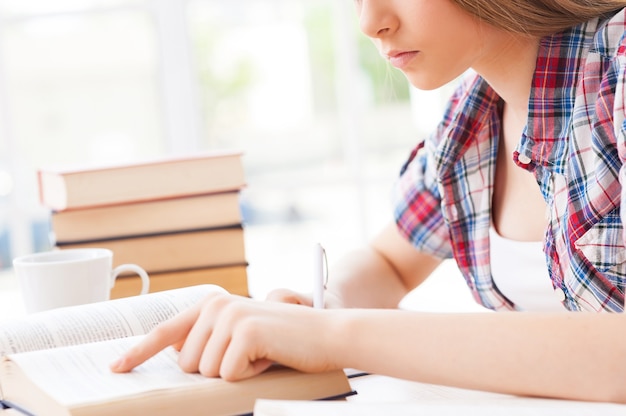 彼女の最終試験の準備。机に座って勉強している10代の少女のトリミングされた画像