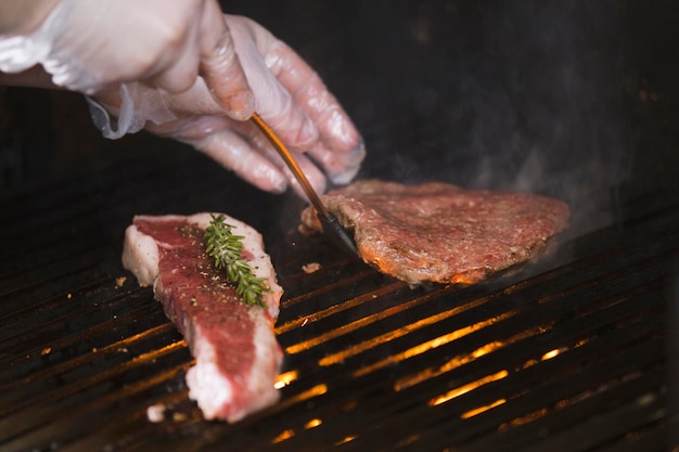 Preparing meat on the grill, chef flips the piece with shovel, concept of cooking and Haute cuisine