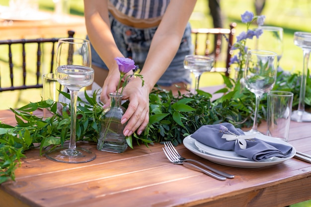 Prepararsi per una festa all'aperto. la ragazza decora i tavoli con fiori freschi. dettagli della decorazione