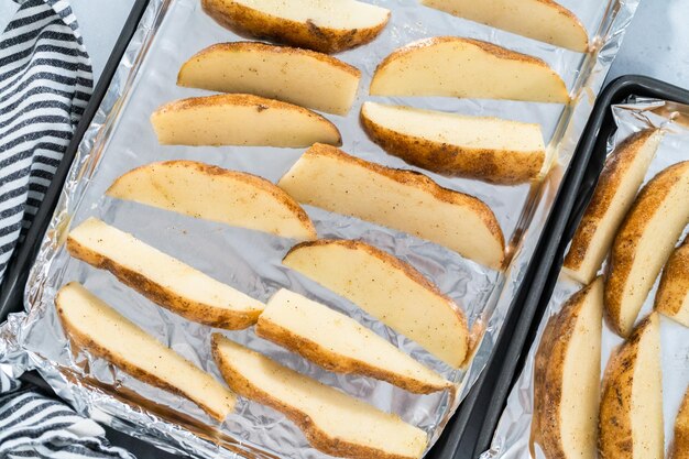 Preparing russet potatoes in wedges with olive oil and spices to bake in the oven