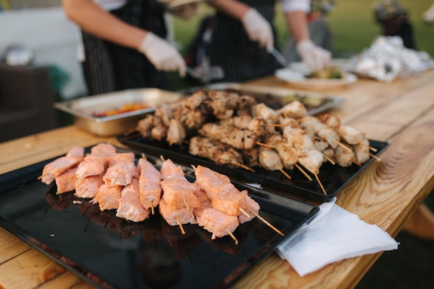 Подготовка курицы из лосося и свинины на вечеринке на открытом воздухе