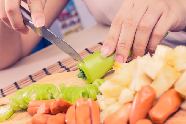 写真 ソーセージと野菜を準備する女性の手はヴィンテージトーン。