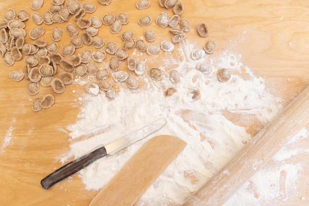 Подготовка южно-итальянской традиционной пасты orecchiette на деревянном столе