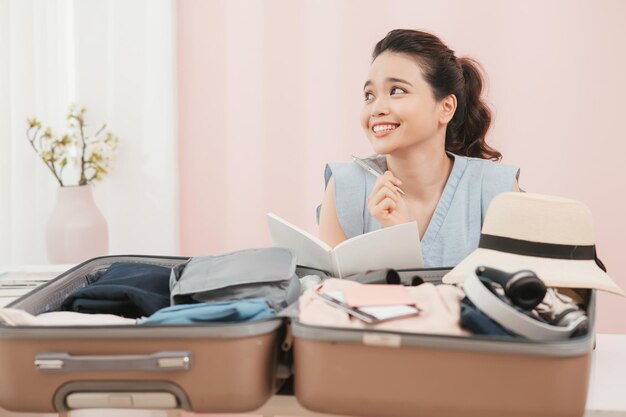 Preparing suitcase for summer vacation trip Young woman checking accessories at home before travel