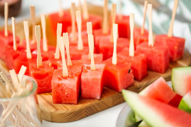 Preparing watermelon appetizers dipped in chocolate and sprinked with sea salt and almonds.