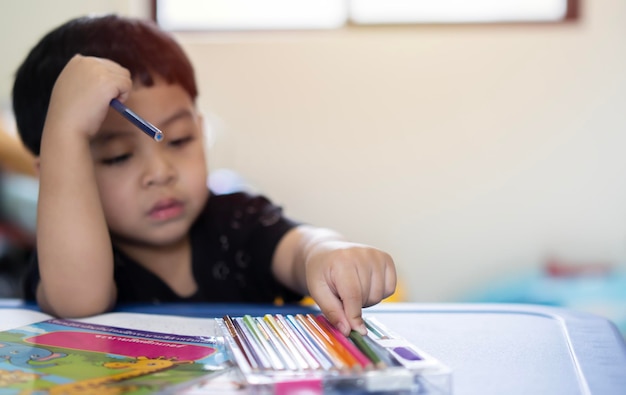 Foto ragazzo asiatico prescolare con matite colorate sulla sua scrivania concetto di ritorno a scuola