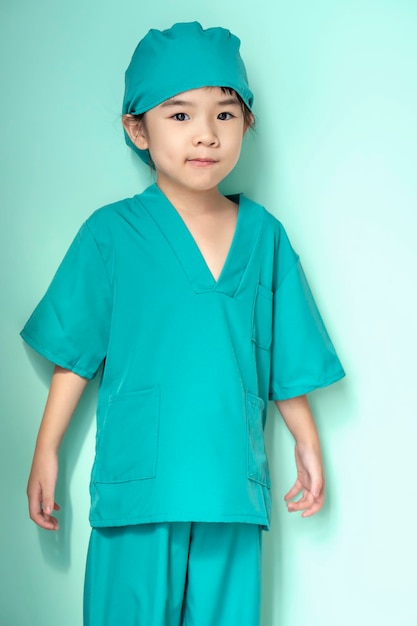 Preschool asian girl child in doctor coat on green isolated background