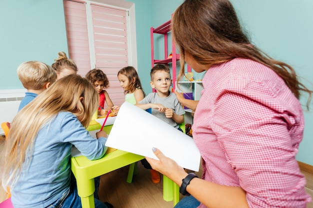 Preschool boy demands teacher's attention during art lesson