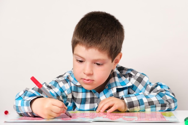 A preschool boy studies and passes labyrinths on a white background