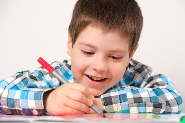 A preschool boy studies and passes labyrinths on a white background