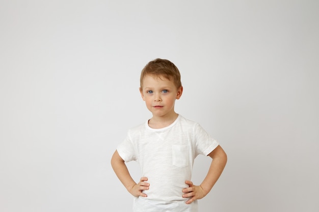 Photo preschool boy with blue eyes stands with his hands on his hips