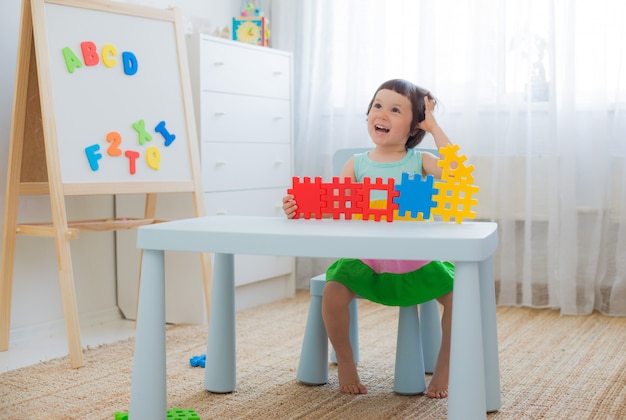 Preschool child 3 years playing with colorful toy blocks.