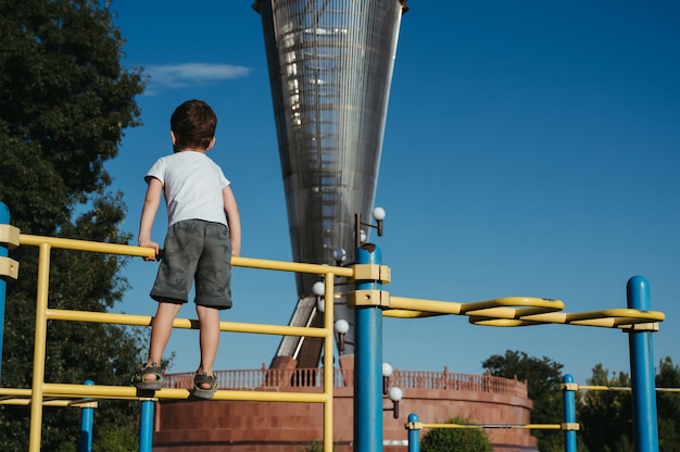 preschool child boy plays on horizontal bars on the playground in the park in summer