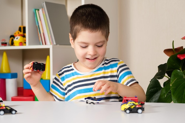 A preschool child plays with toy cars sitting at a table at home