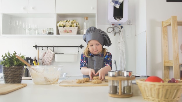 写真 就学前の女の子のパン屋は、ベーキングシートのクローズアップにビスケットを置きます